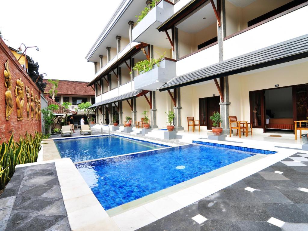 a swimming pool in front of a building at Jesens Inn II in Kuta