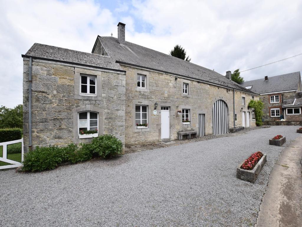 an old stone building with a gate and a driveway at Cozy Wéris cottage retreat in Weris