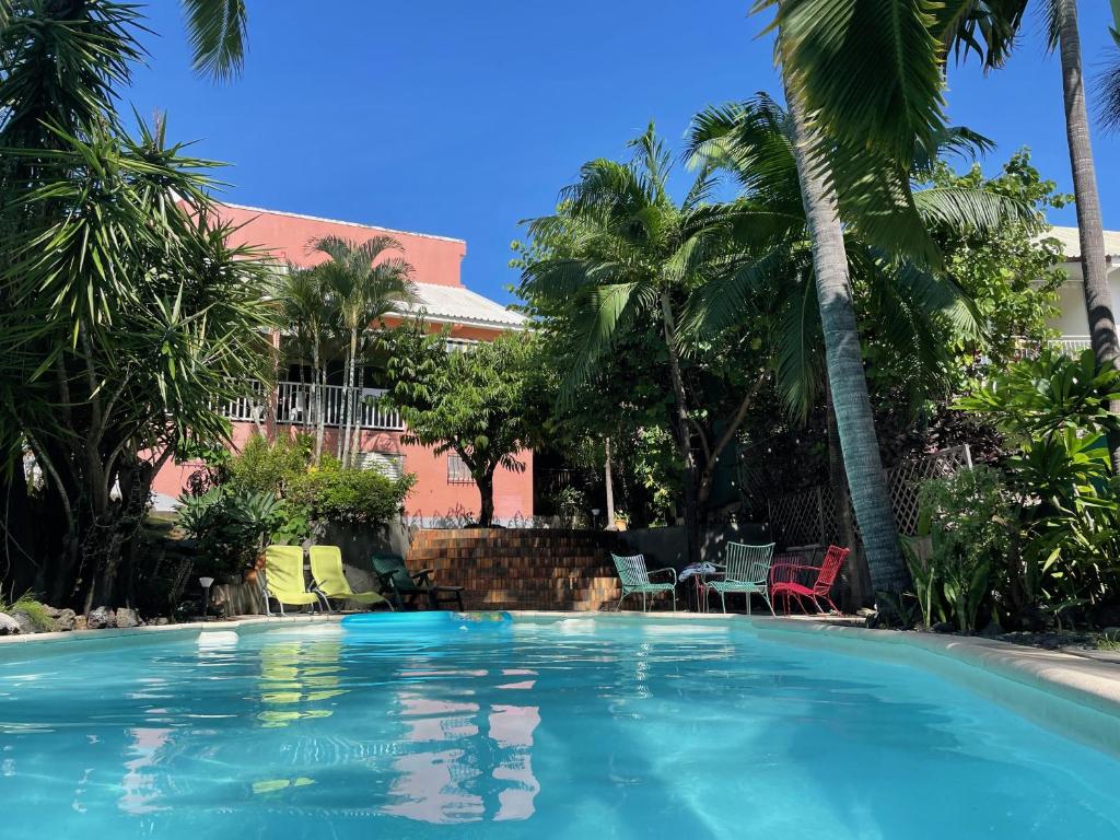 a swimming pool with palm trees and a building at Villa KazAlizés avec Piscine et Jardin Saint Leu in Saint-Leu