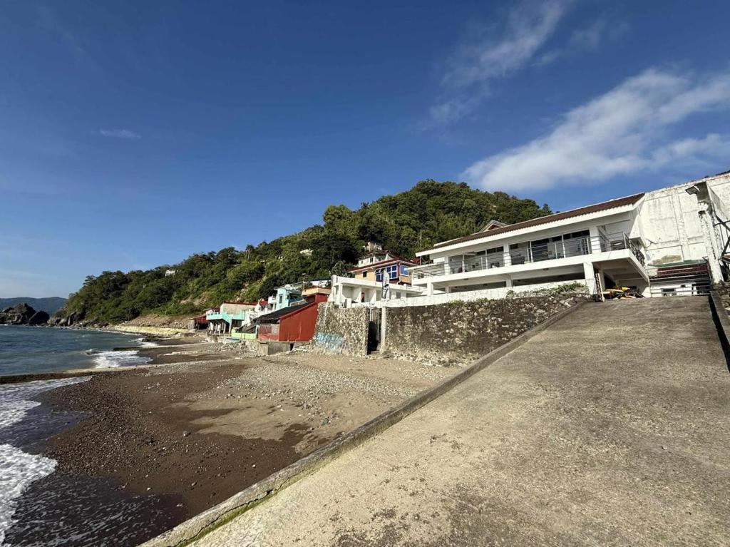 a building on the beach next to the water at Villa Ebarle Diving Resort in Mabini