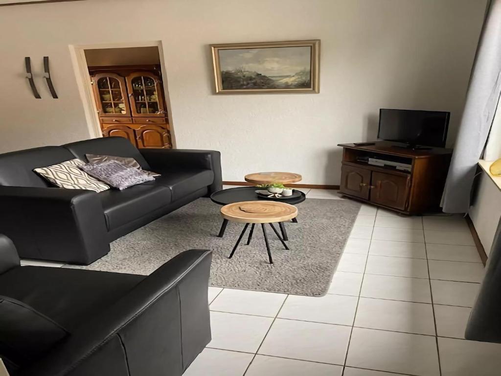 a living room with a black couch and a table at Holiday Home in Margraten near Maastricht in Margraten