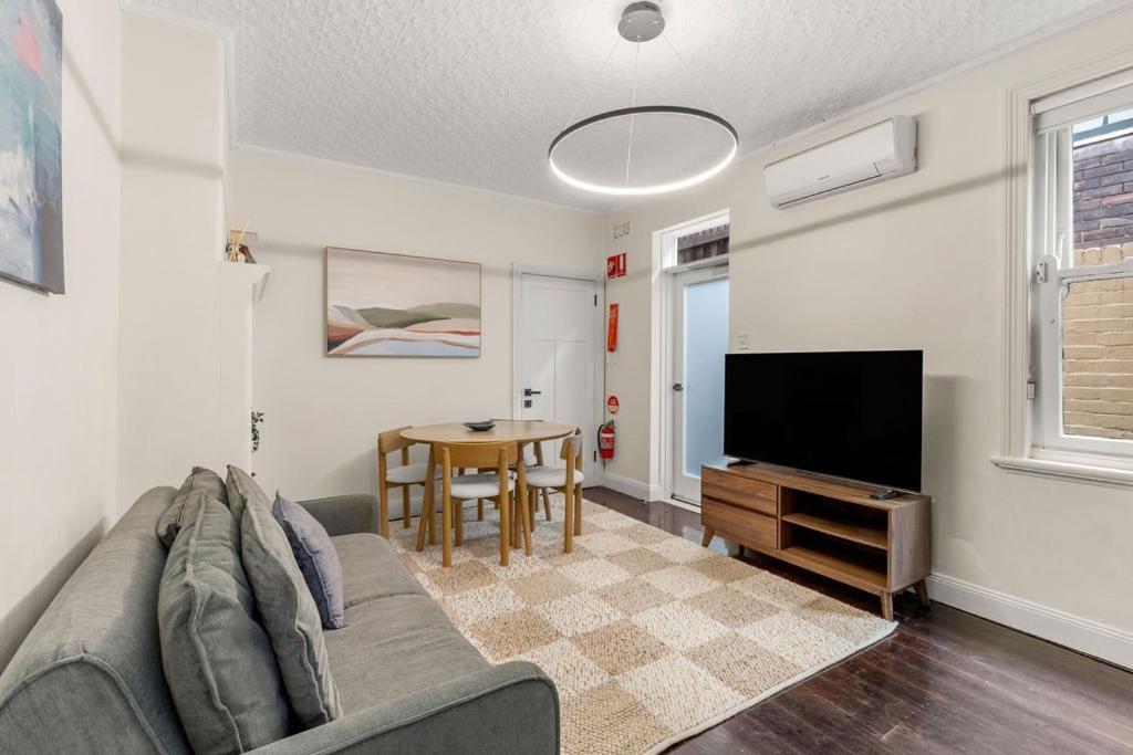 a living room with a couch and a flat screen tv at Millers Point Retreat 5 Min Walk to Barangaroo in Sydney