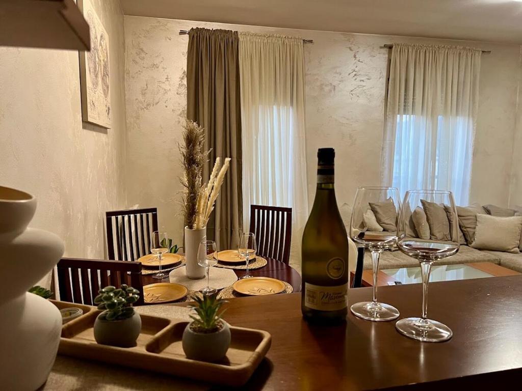 a dining room table with a bottle of wine and glasses at Cozy Modern Apartment Podgorica in Podgorica