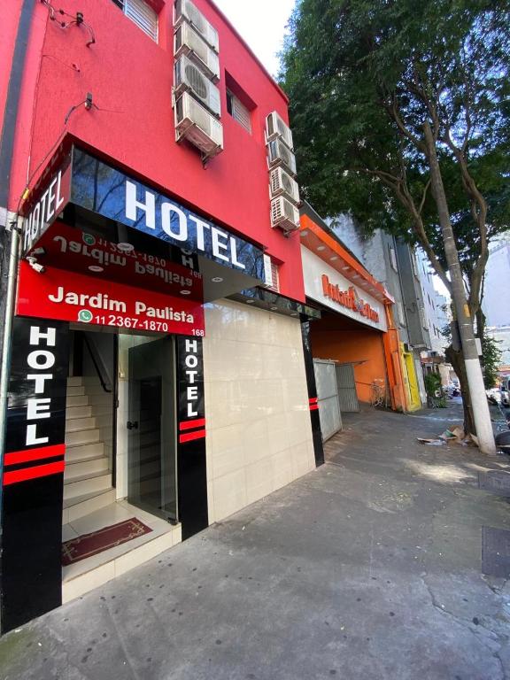 a red building with a hotel sign on a street at Hotel jardim paulista in São Paulo