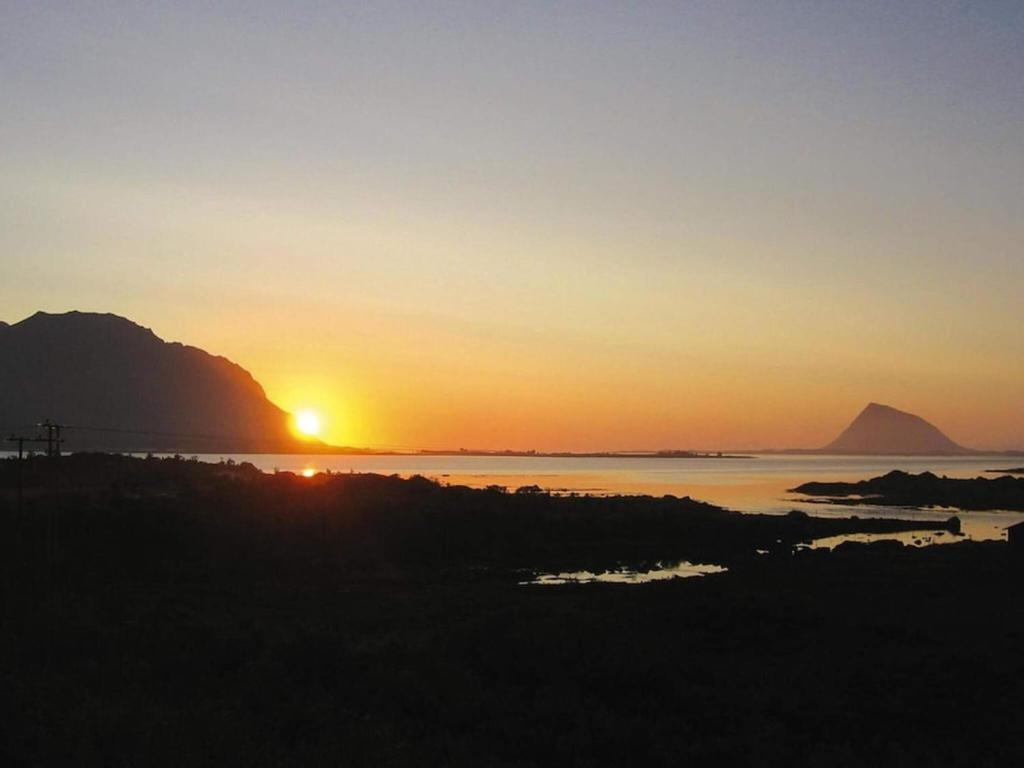 a sunset over the water with mountains in the background at 7 person holiday home in Bøstad in Alstad