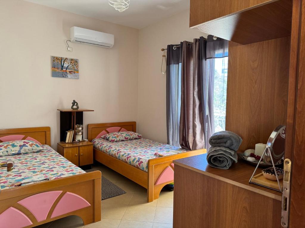een slaapkamer met twee bedden en een raam bij Travellers Room in Sarandë
