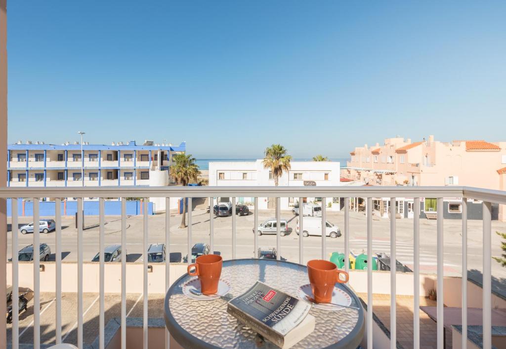 a balcony with a table with a book and coffee cups at Apartamento Gaviotas Sureñas in Tarifa