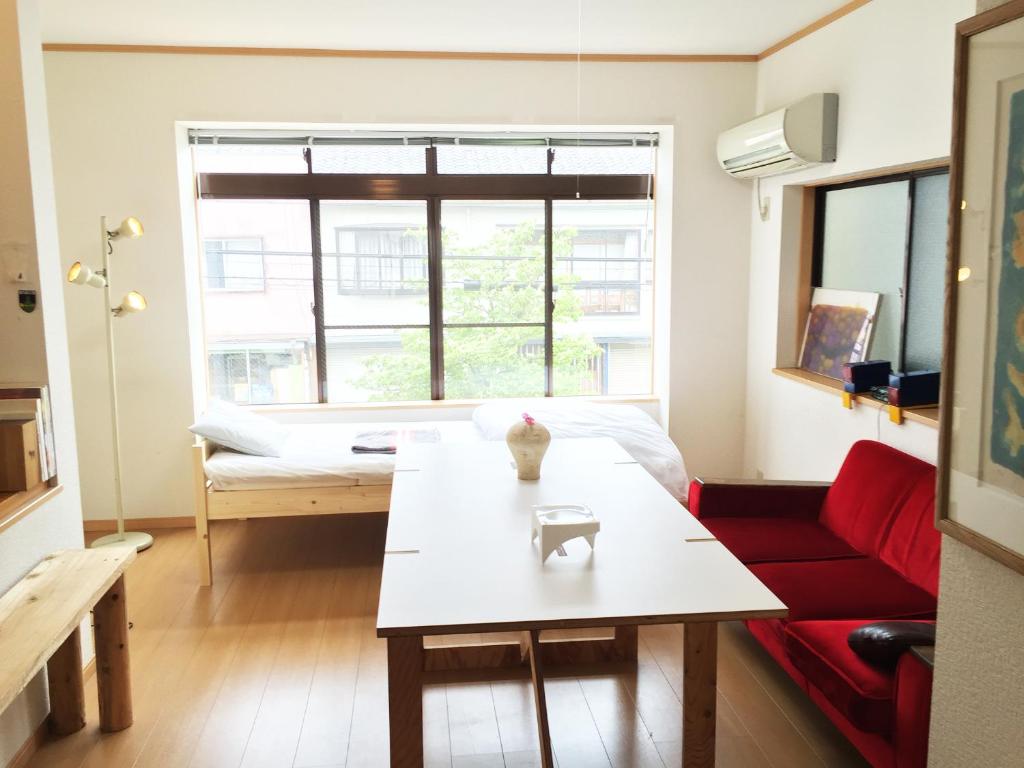 富山市にあるトゥーレイト ゲストハウス富山のリビングルーム(テーブル、赤いソファ付)