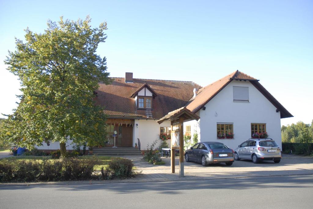 ein Haus mit zwei Autos, die davor geparkt sind in der Unterkunft Gasthaus-Pension Hofmann in Oberdachstetten