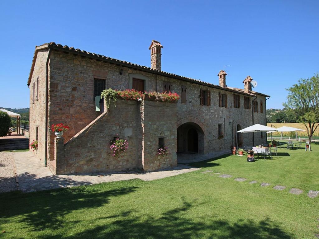 Un edificio con flores en el costado. en Apartment on farm amidst the Umbrian hills, en Todi