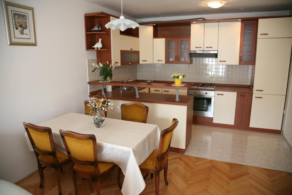 eine Küche mit einem Tisch und Stühlen sowie eine Küche mit weißen Schränken in der Unterkunft Apartment DG with parking garage in Split