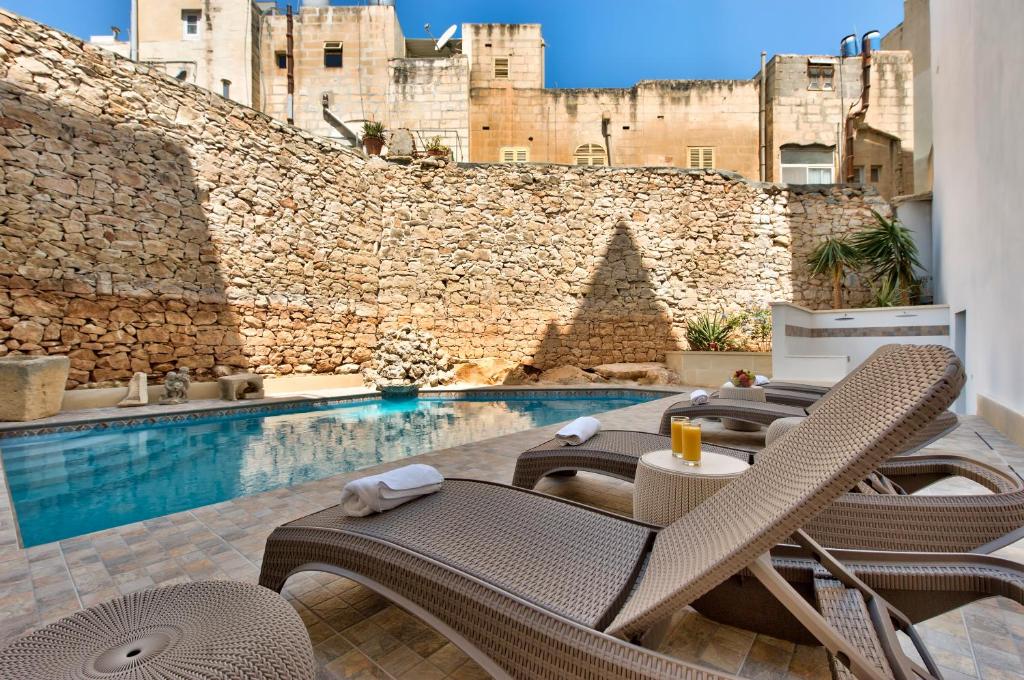a patio with chairs and a swimming pool at Palazzo Violetta Boutique Hotel in Sliema
