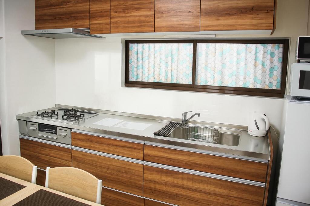 a kitchen with wooden cabinets and a sink and a microwave at Mic HANEDA in Tokyo