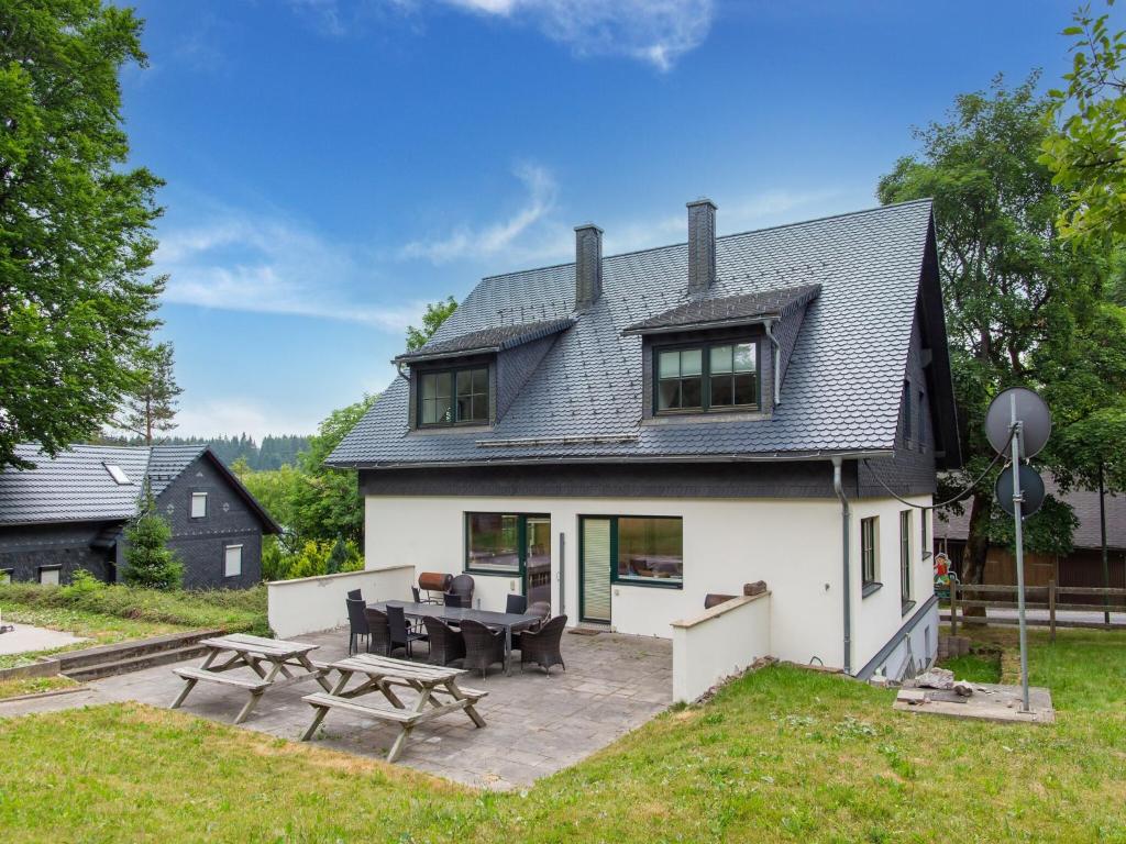 a large white house with a patio in front of it at Spacious semi-detached house with wood stove located directly on the Rennsteig in Eisfeld