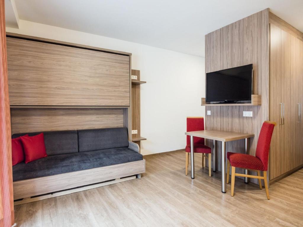 Un dormitorio con una cama, una mesa y un televisor. en Apartment in Kleinarl near Ski-Area with Balcony & Parking, en Kleinarl