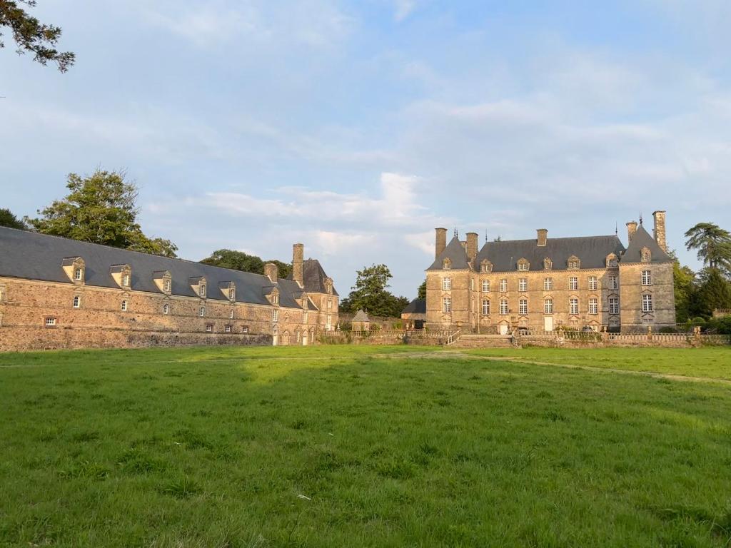 an old castle with a grass field in front of it at Les Communs de Chiffrevast in Tamerville
