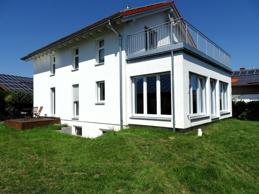 a white house with a balcony on top of a yard at Sunny house, 2 residential units in Postmünster
