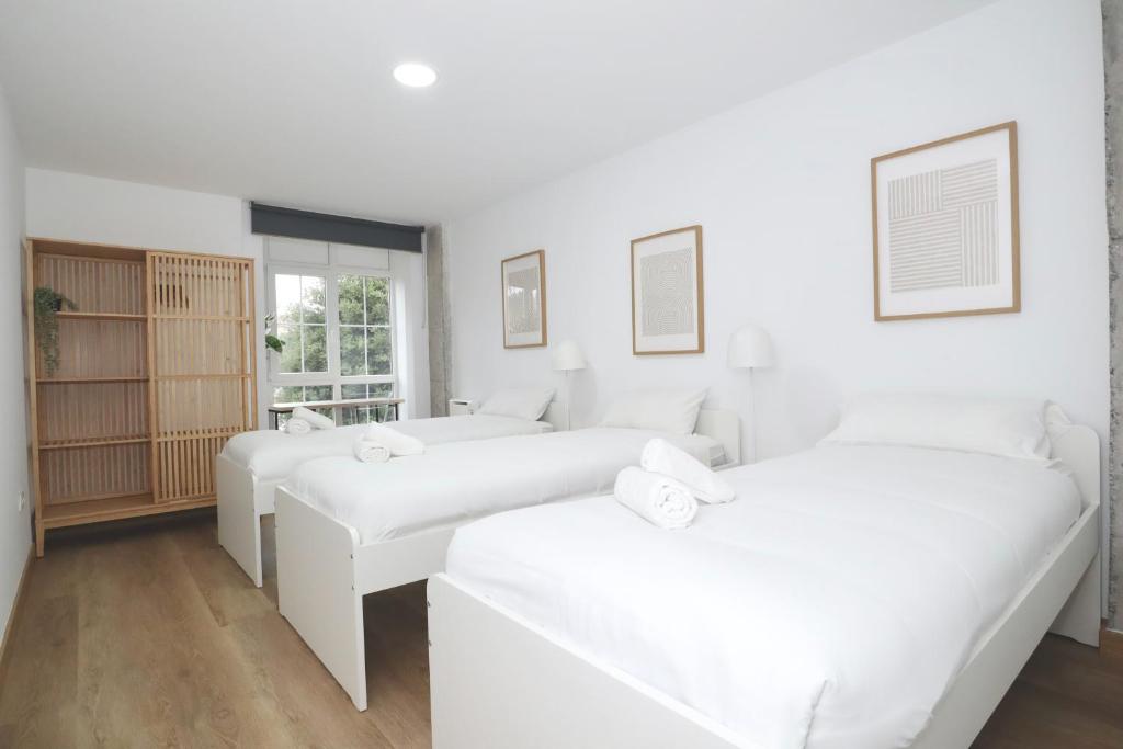 two beds in a room with white walls at Notel Club - Apt Somo Surf in Somo