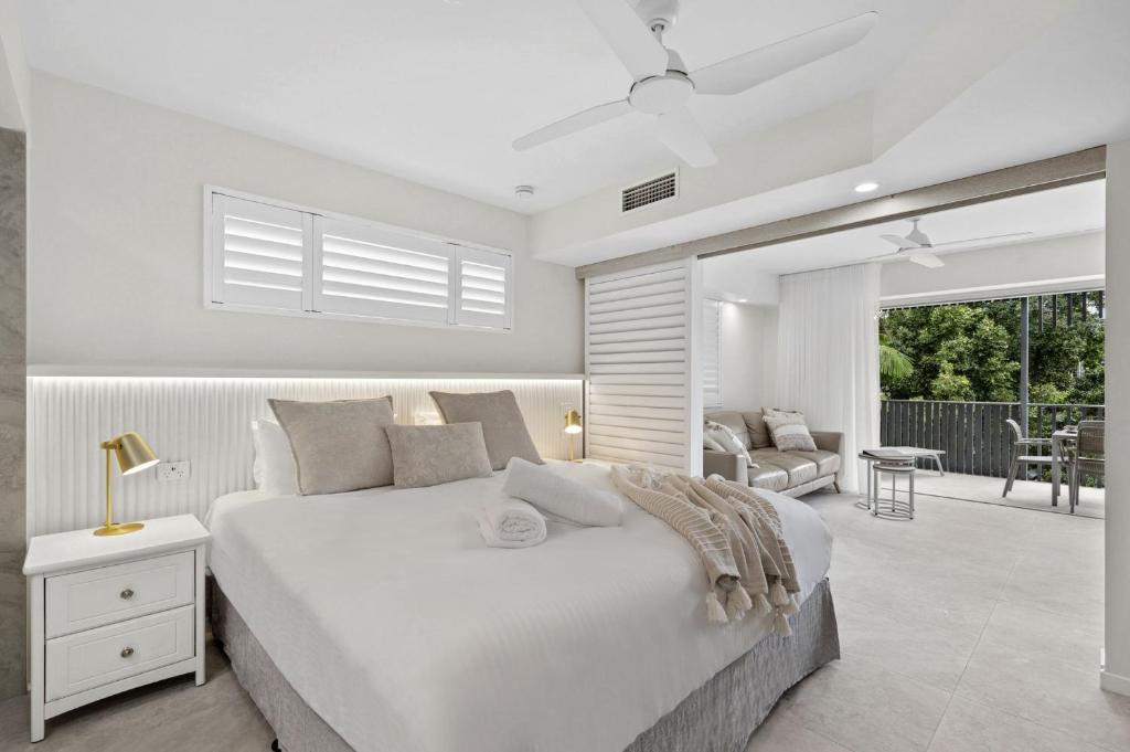 ヌーサヘッズにあるFrench Quarter by Stay Noosaの白いベッドルーム(大型ベッド1台付)、パティオが備わります。