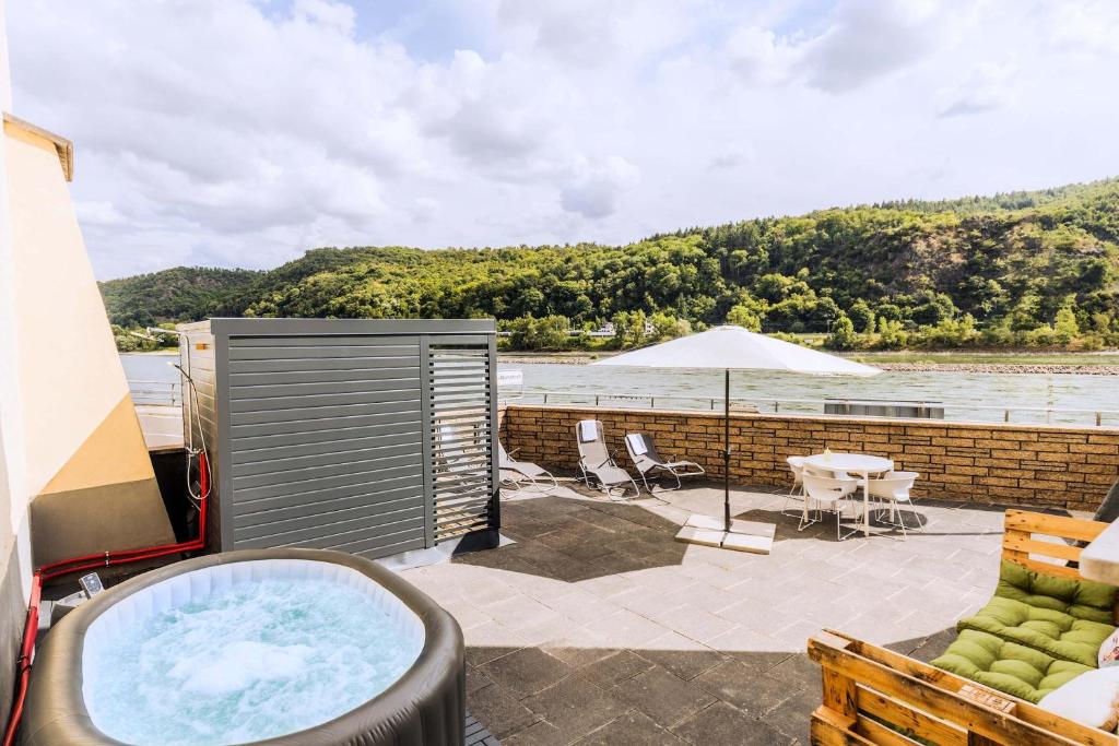 a hot tub on a patio next to the water at Villa Klosterschenke Sauna Whirlpool Game Room in Sankt Goarshausen