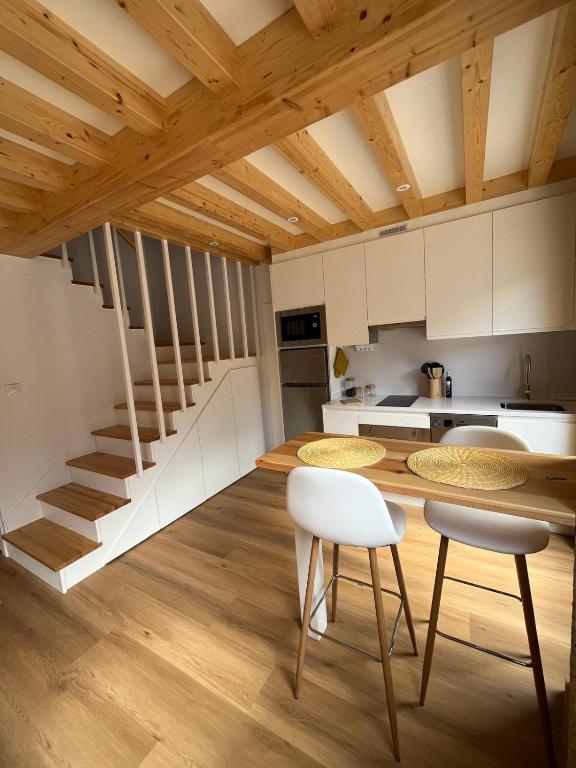 a kitchen with white cabinets and a wooden table and chairs at A de Laura in Lariño
