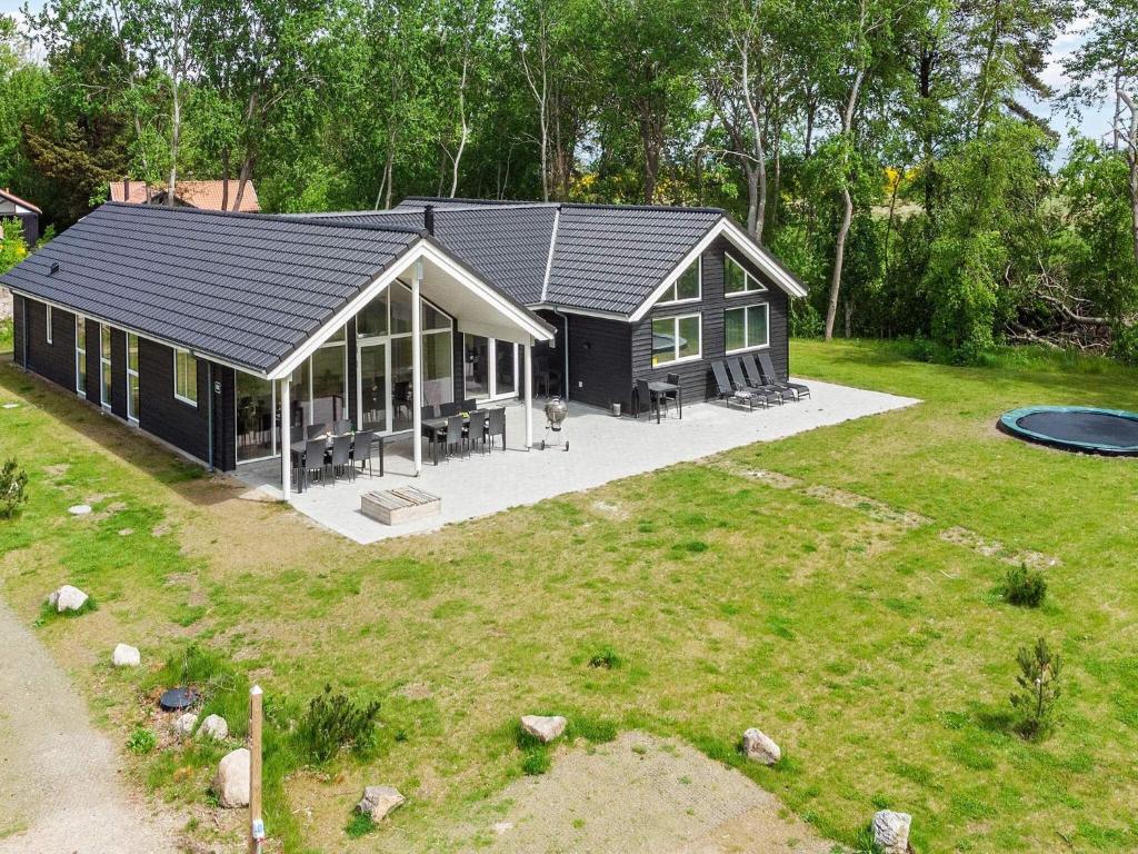 a black house with a large yard with a frisbee at 18 person holiday home in Væggerløse in Marielyst