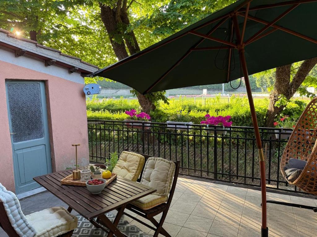 eine Terrasse mit Tisch und Stühlen und einem Sonnenschirm in der Unterkunft Vintage cottage-style cottage near the park in Abbadia San Salvatore