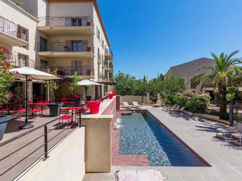 un hôtel avec une piscine à côté d'un bâtiment dans l'établissement Garrigae Distillerie de Pezenas - Hotellerie & Spa, à Pézenas