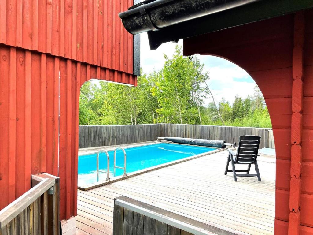 a red building with a swimming pool on a wooden deck at 5 person holiday home in ULRIKA in Rimforsa