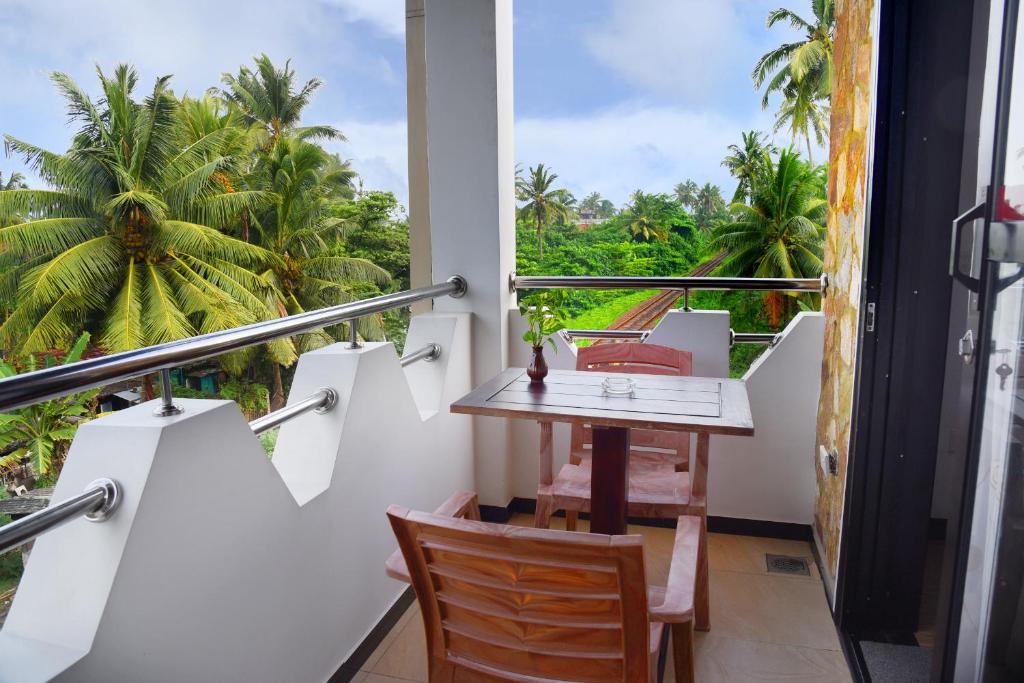 a balcony with a table and chairs and palm trees at L&D Lodge in Hikkaduwa