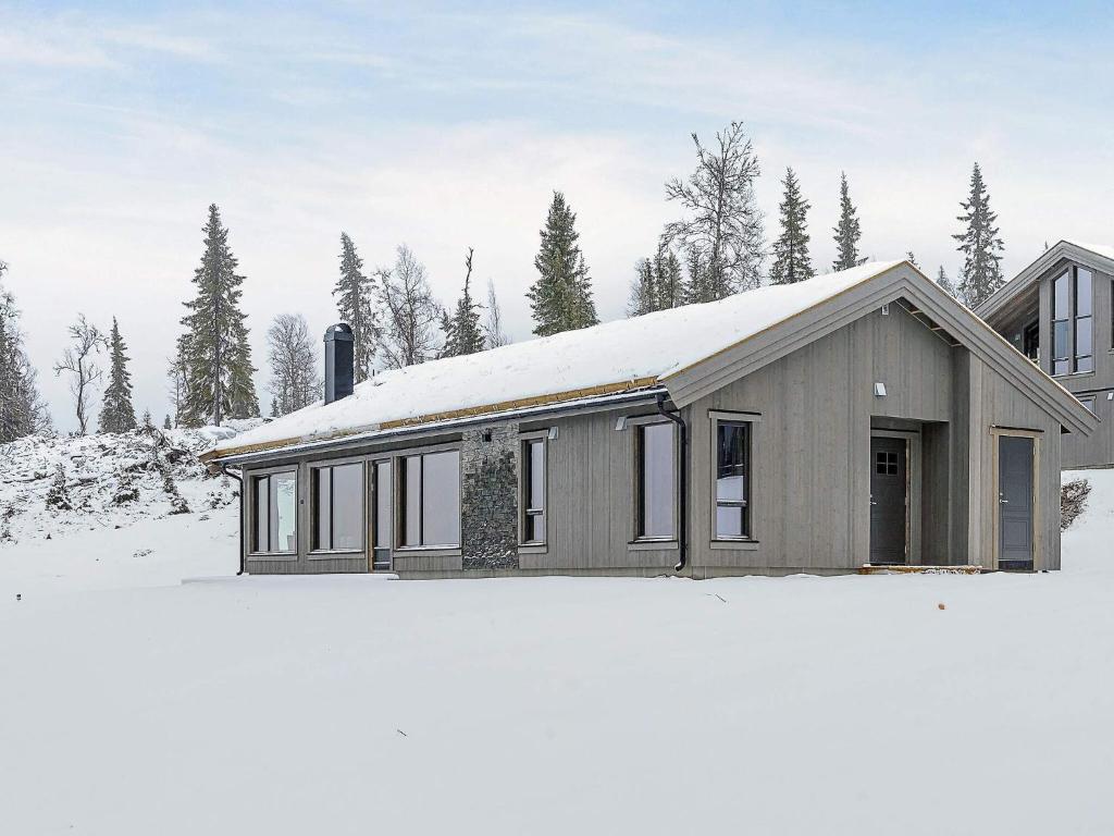 a house with a snow covered roof in the snow at 10 person holiday home in Fåvang in Favang