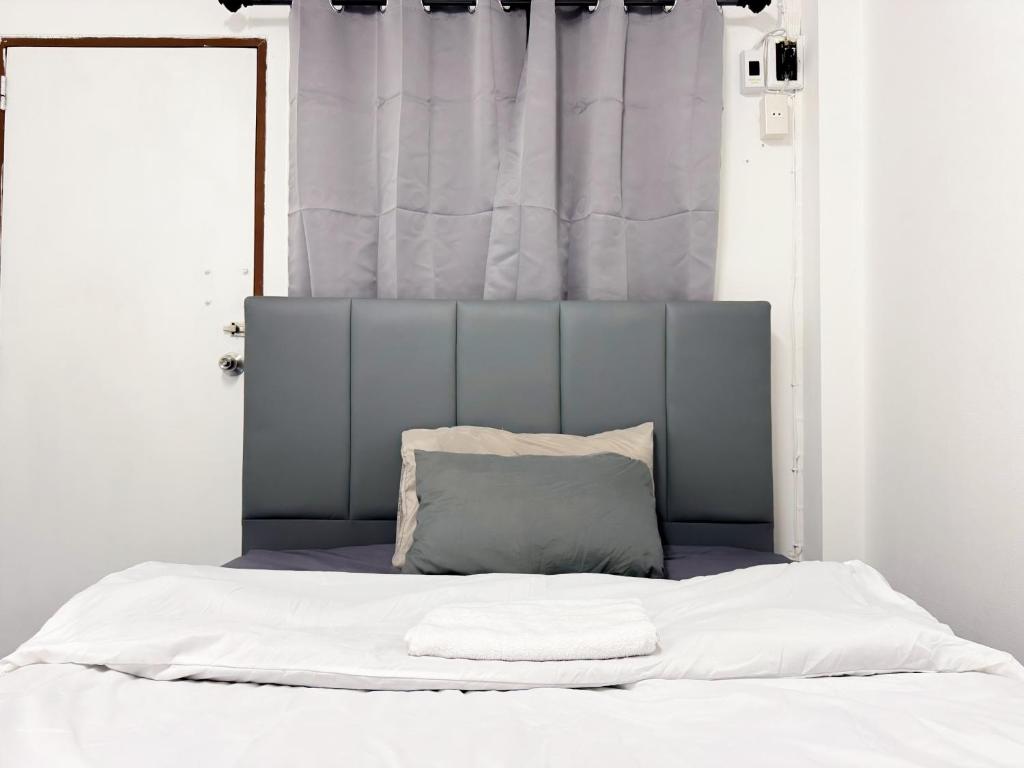 a bed with a gray headboard and a pillow at ฐิติพร อพาร์ทเม้นต์ บางเขน in Ban Ko