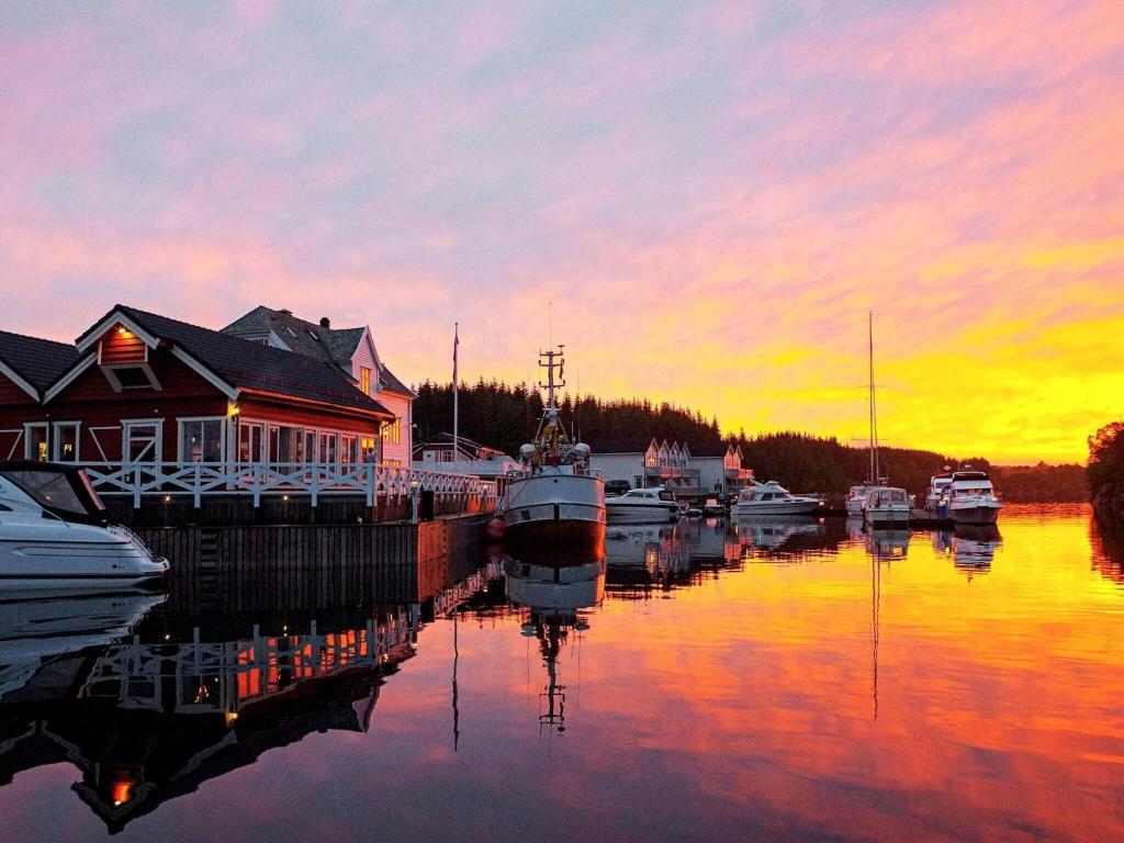 een groep boten aangemeerd in een jachthaven bij zonsondergang bij 6 person holiday home in Austrheim in Utkeila