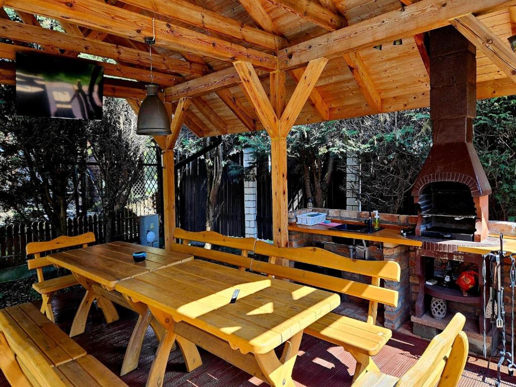 a wooden picnic table and chairs on a patio with a fireplace at Comfortable house with private pool, Kolczewo in Kołczewo