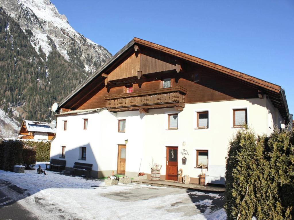 a large white building with a wooden roof at Farmhouse in Ötztal near Ski Areas in Längenfeld