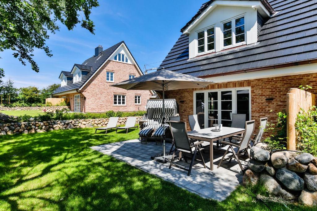 een terras met een tafel, stoelen en een parasol bij Haus Dock 10 in Westerland