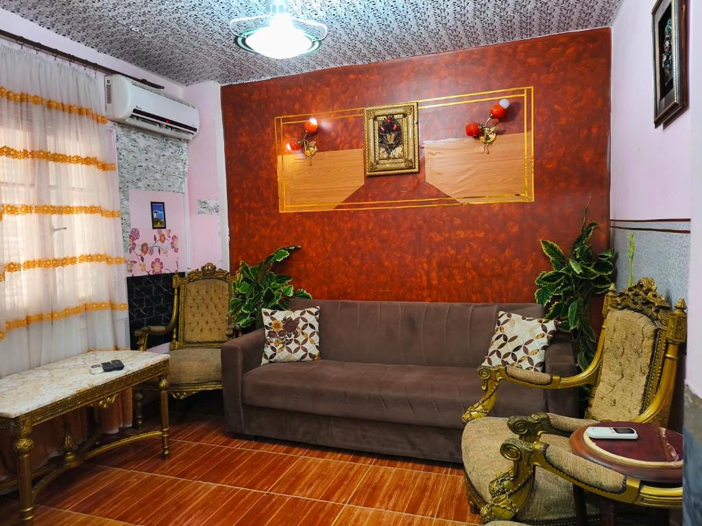 ein Wohnzimmer mit einem Sofa und einer roten Wand in der Unterkunft Fayrouzat Near the sea with garden Vew in Alexandria