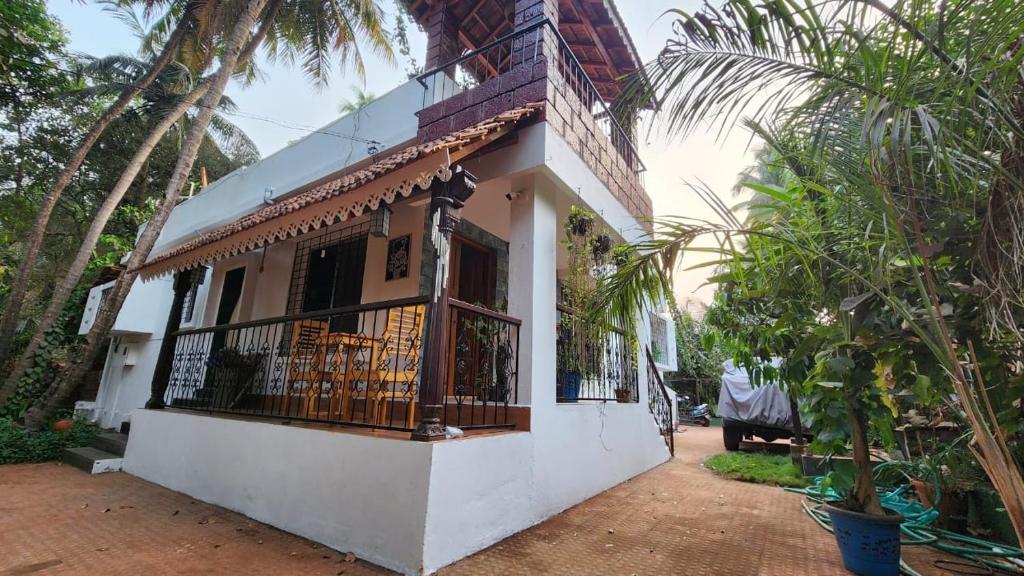 a white house with a balcony and palm trees at Bhatye Beach Resort Rejunuvation in Ratnagiri