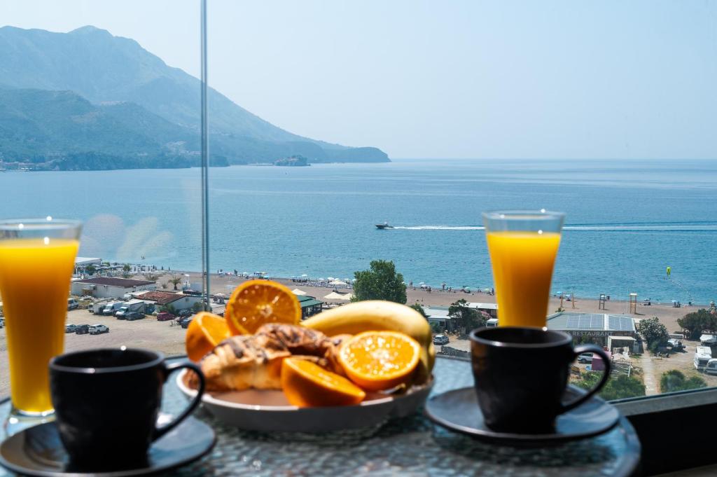 a table with a plate of food and two glasses of orange juice at Apartman Katica in Bečići