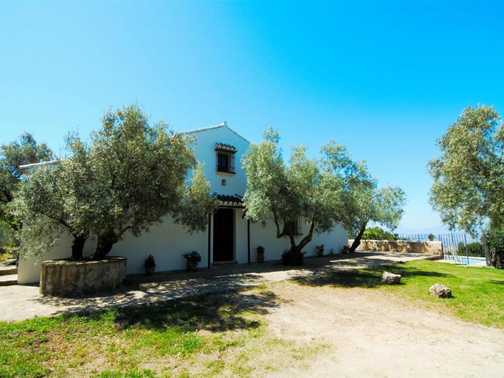 a white house with trees in front of it at Cottage in Antequera with Pool near El Torcal in La Joya