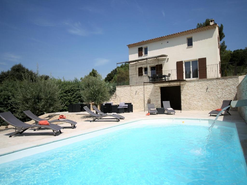 a large swimming pool with chairs and a house at Villa in Lubéron with Saltwater Pool in Apt