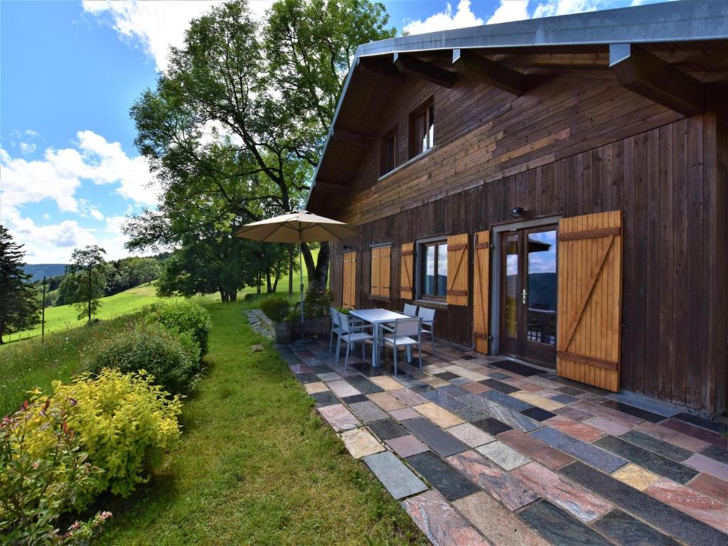 a patio with a table and an umbrella next to a building at Chalet in Saulxures near Ski Resorts in Saulxures-sur-Moselotte