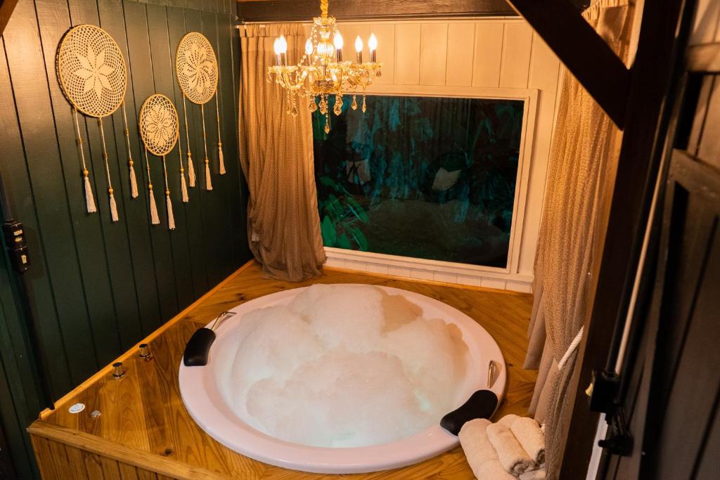a bath tub in a bathroom with a chandelier at Cabana Lake Side Refúgio Charmoso no Vale Europeu in Benedito Novo