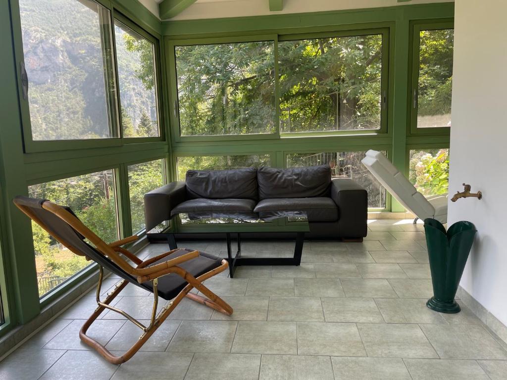 a living room with a couch and a chair at Villa fleurie - maison familiale, véranda et jardin in Tende