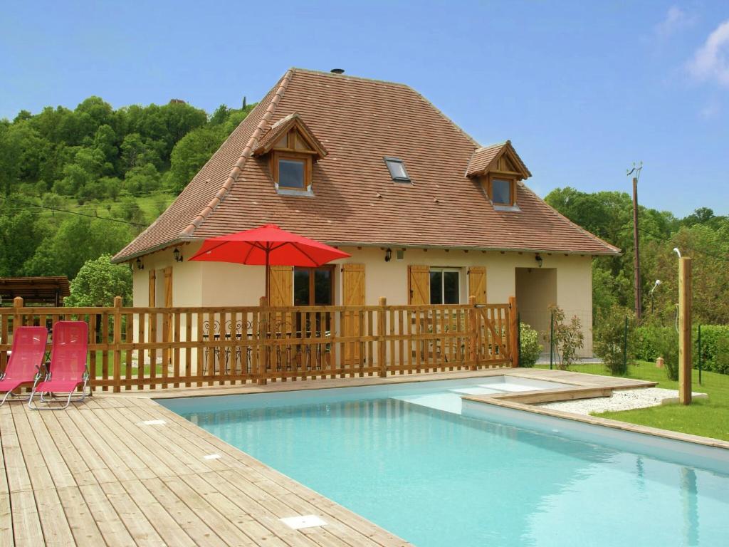 a house with a pool with two chairs and a red umbrella at Nature Escape in Loubressac in Loubressac