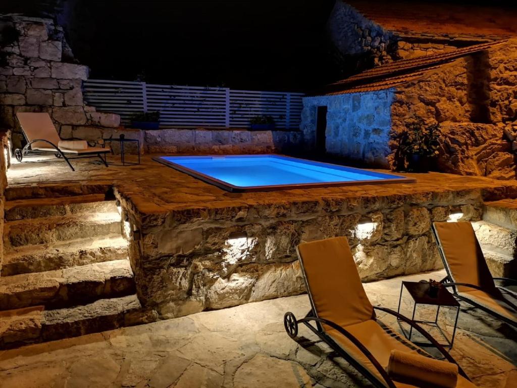 una piscina con dos sillas y una mesa en Stone House in Brotnice near Cavtat & Sea, en Cavtat