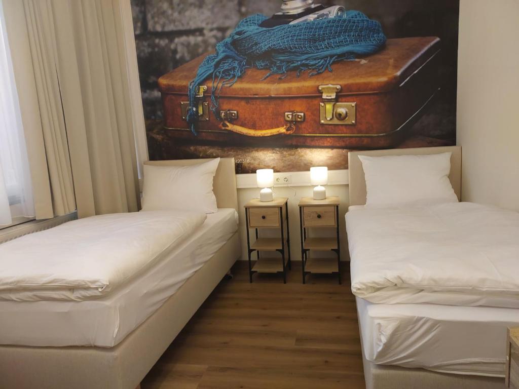 two beds in a room with a suitcase on the wall at Renatus Apartments in Eschau