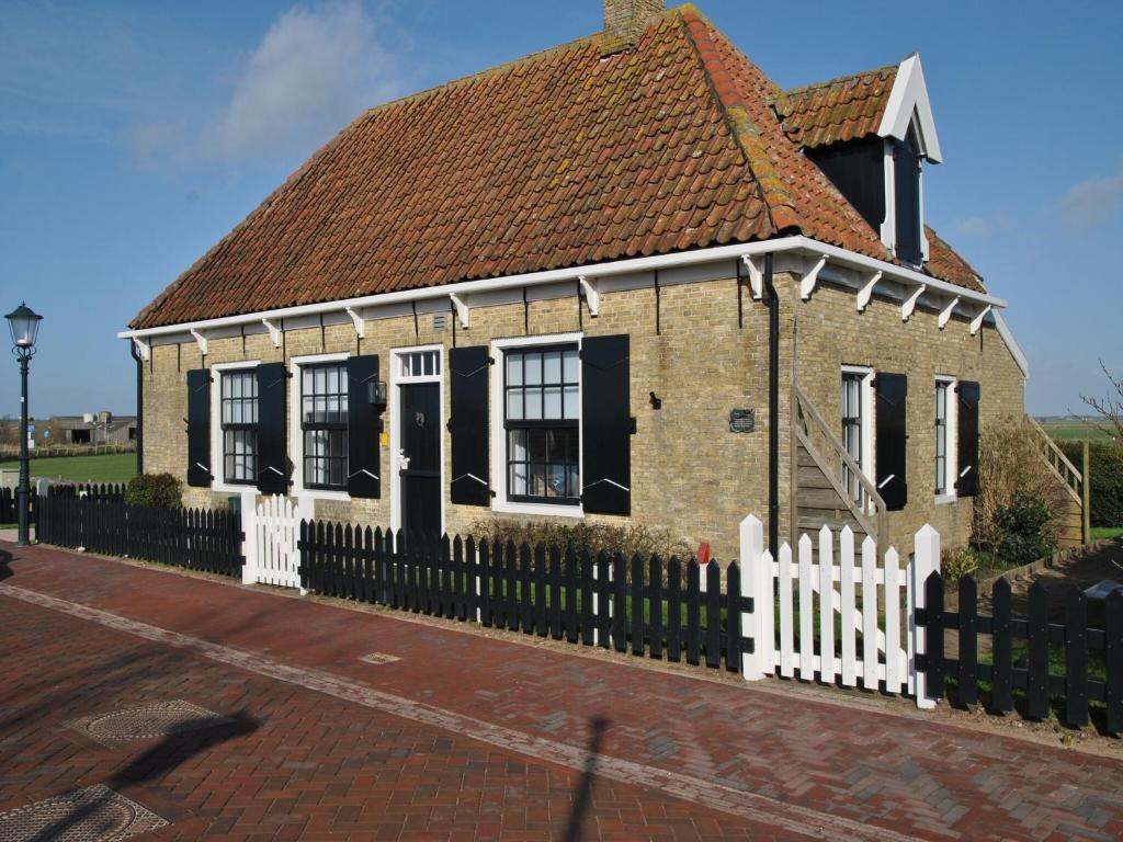 a small brick house with a white fence at Holiday Home in Texel near Sandy Beaches in Den Hoorn
