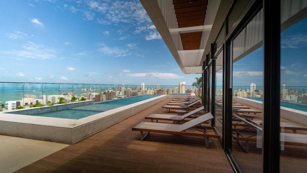 einen Pool auf dem Dach eines Gebäudes mit Stühlen in der Unterkunft Vento Terral - 42m, Novo, Alto Padrão, Frente Mar in Fortaleza