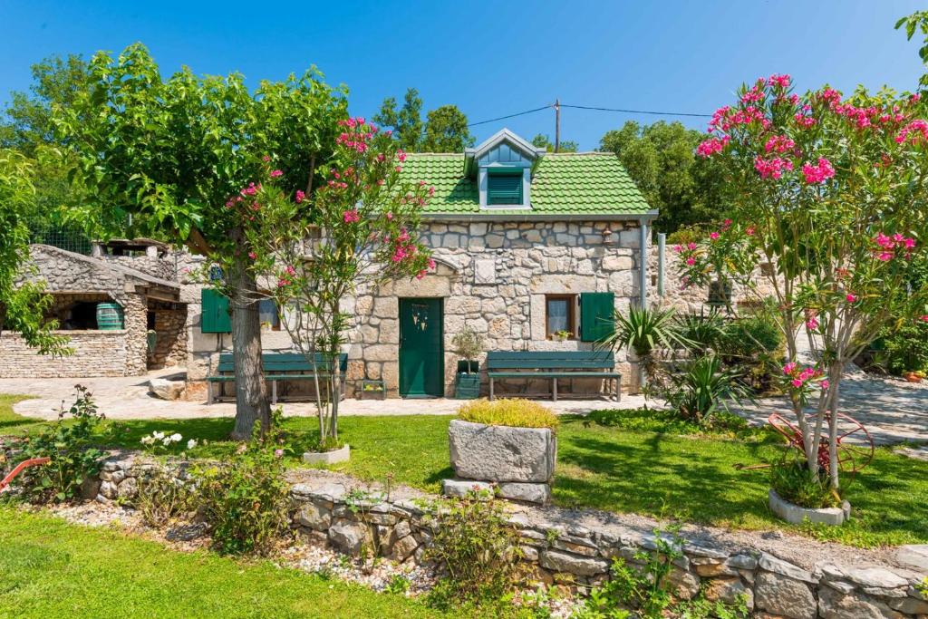 a stone house with a garden with pink flowers at Villa Heritage Harmony with private pool in Zmijavci
